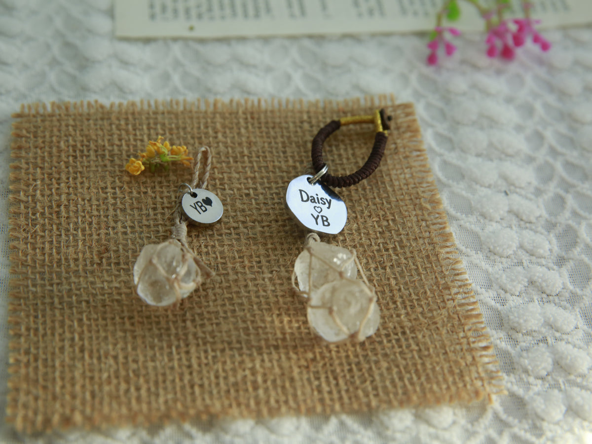 Beige cord clear quartz pet pendant beside a two-stone owner charm with engraved round tags