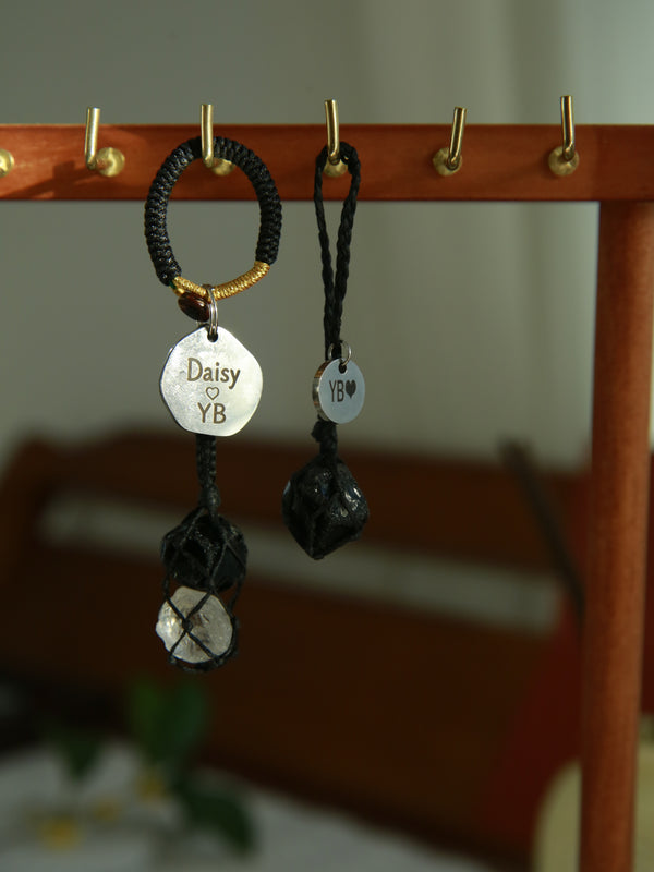 Black cord owner charm with obsidian and clear quartz beside a single obsidian pet pendant