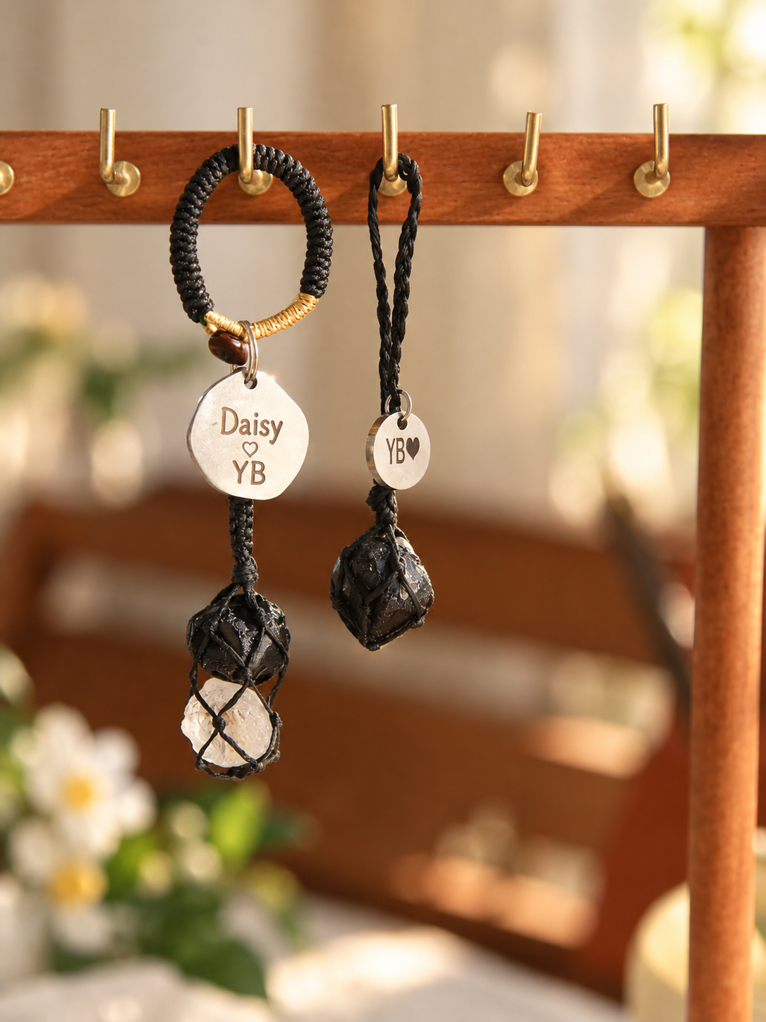 Black obsidian pet pendant and matching obsidian and Clear Quartz owner bag charm hanging from a wooden display, with personalized round tags