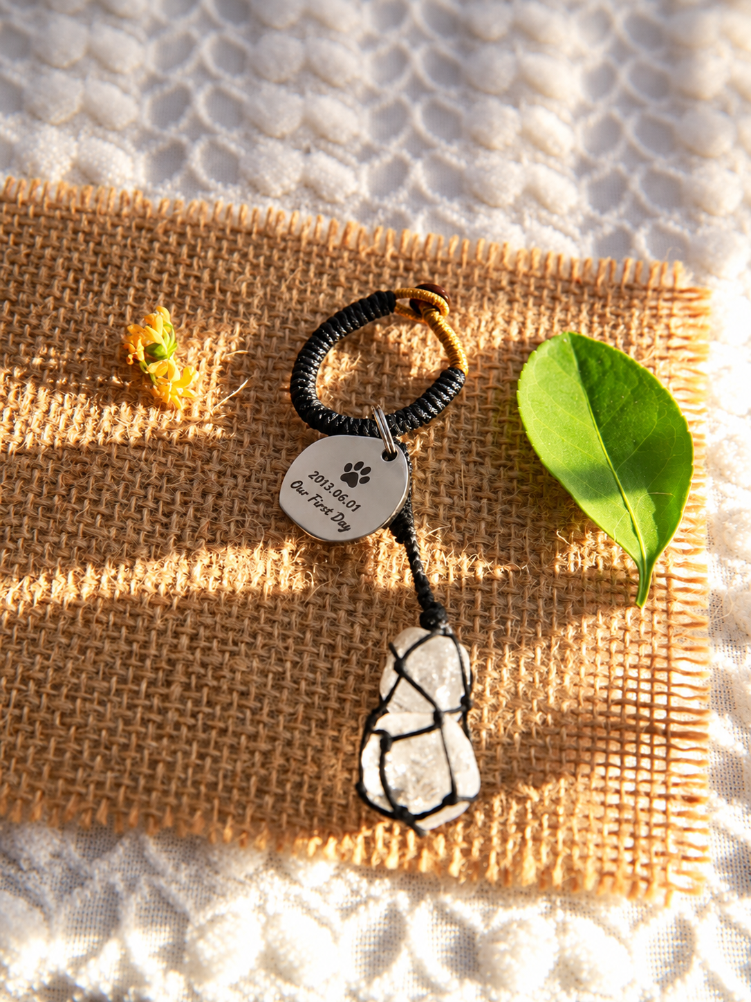 Black waxed cord bag charm with two natural Clear Quartz stones, showing the tag back engraved with a paw print, date and Our First Day